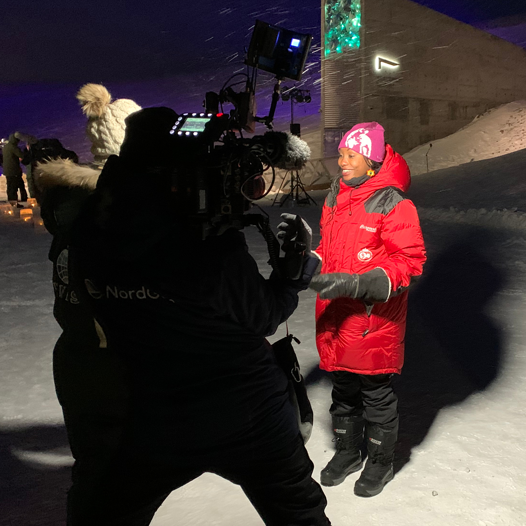 Filmopptak utendørs i snølandskap med programleder i rødt – innholdsproduksjon i arktiske omgivelser med Medvind Eventbyrå.